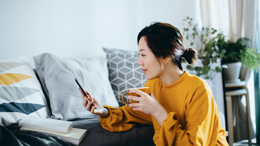Hand typing on laptop, with coffee and notebooks on table.