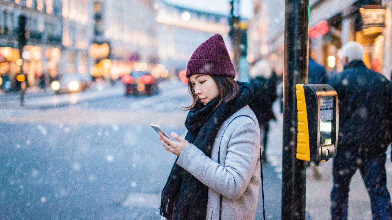 An Asian girl is using smartphone on the street;imaged used for HSBC Singapore 9 essential foreign exchange travel tips article