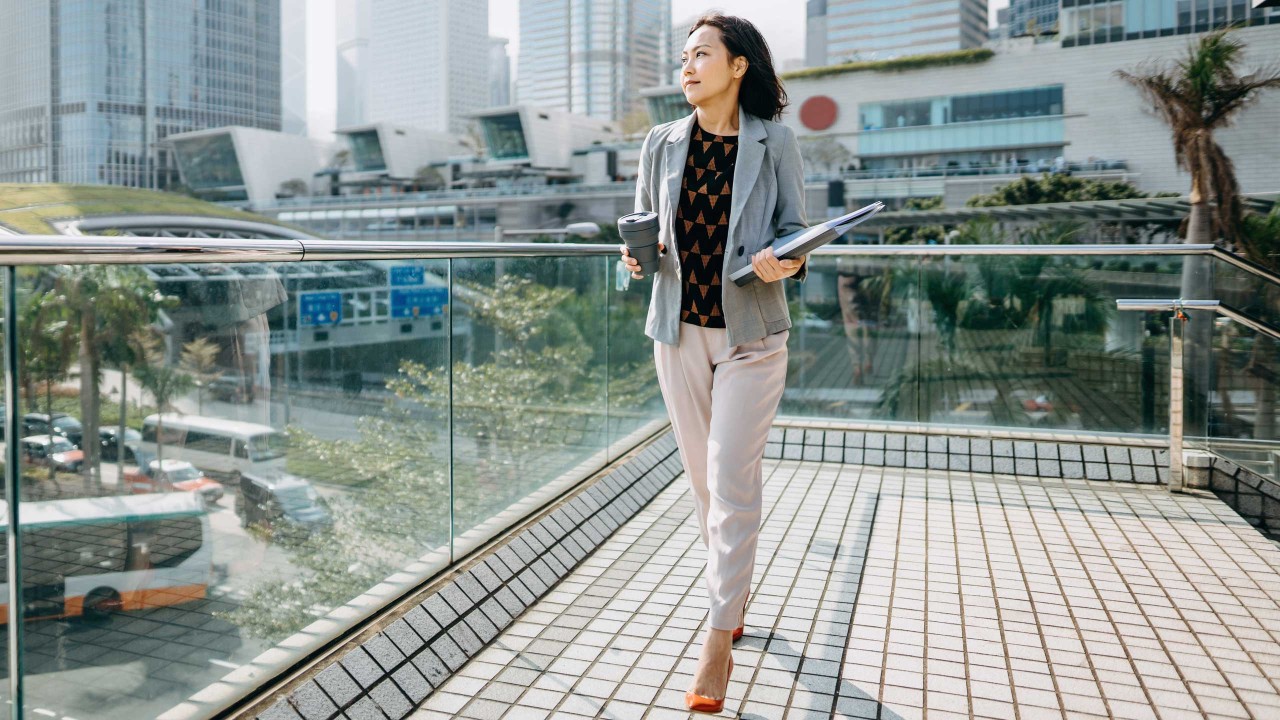 A businesswoman looking away and holding documents and coffee