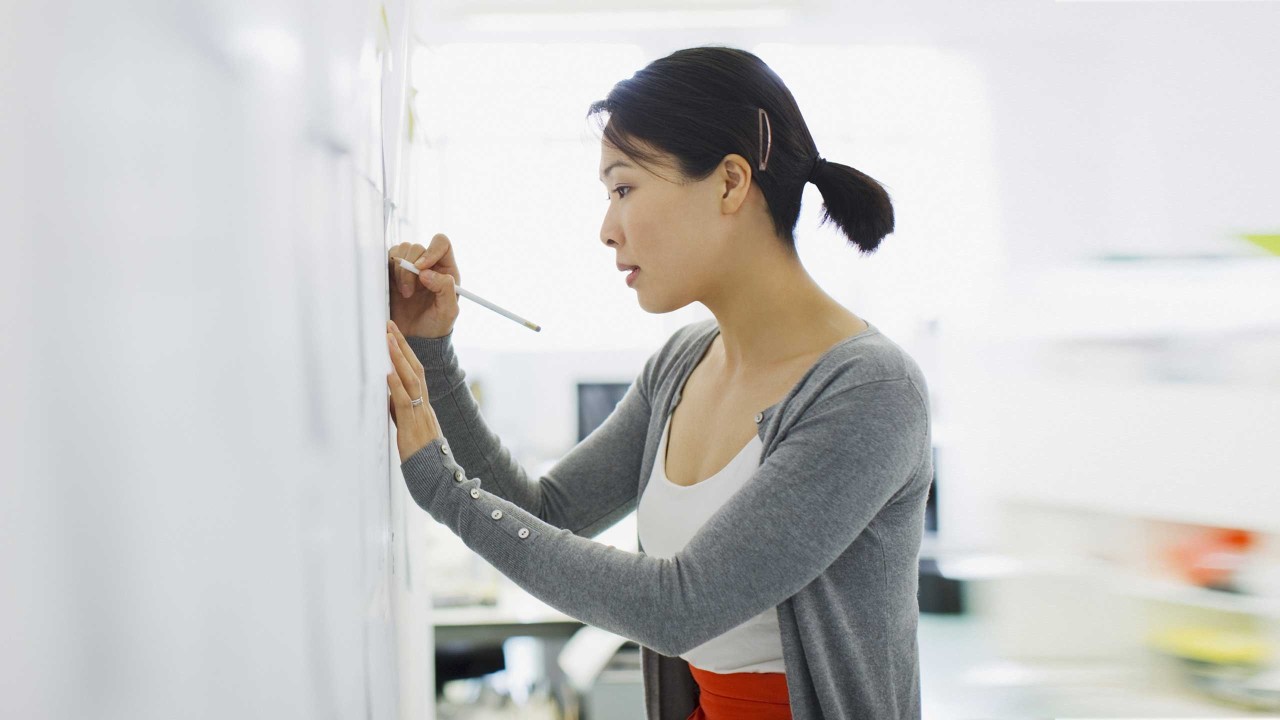 A businesswoman writing on whiteboard