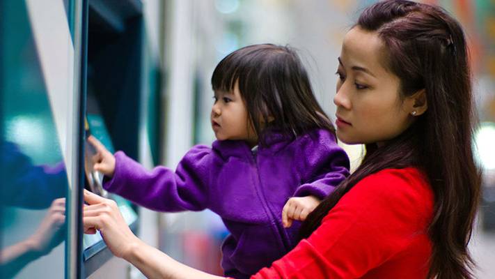 A woman using cash machine with kid; image used for HSBC Singapore Express banking