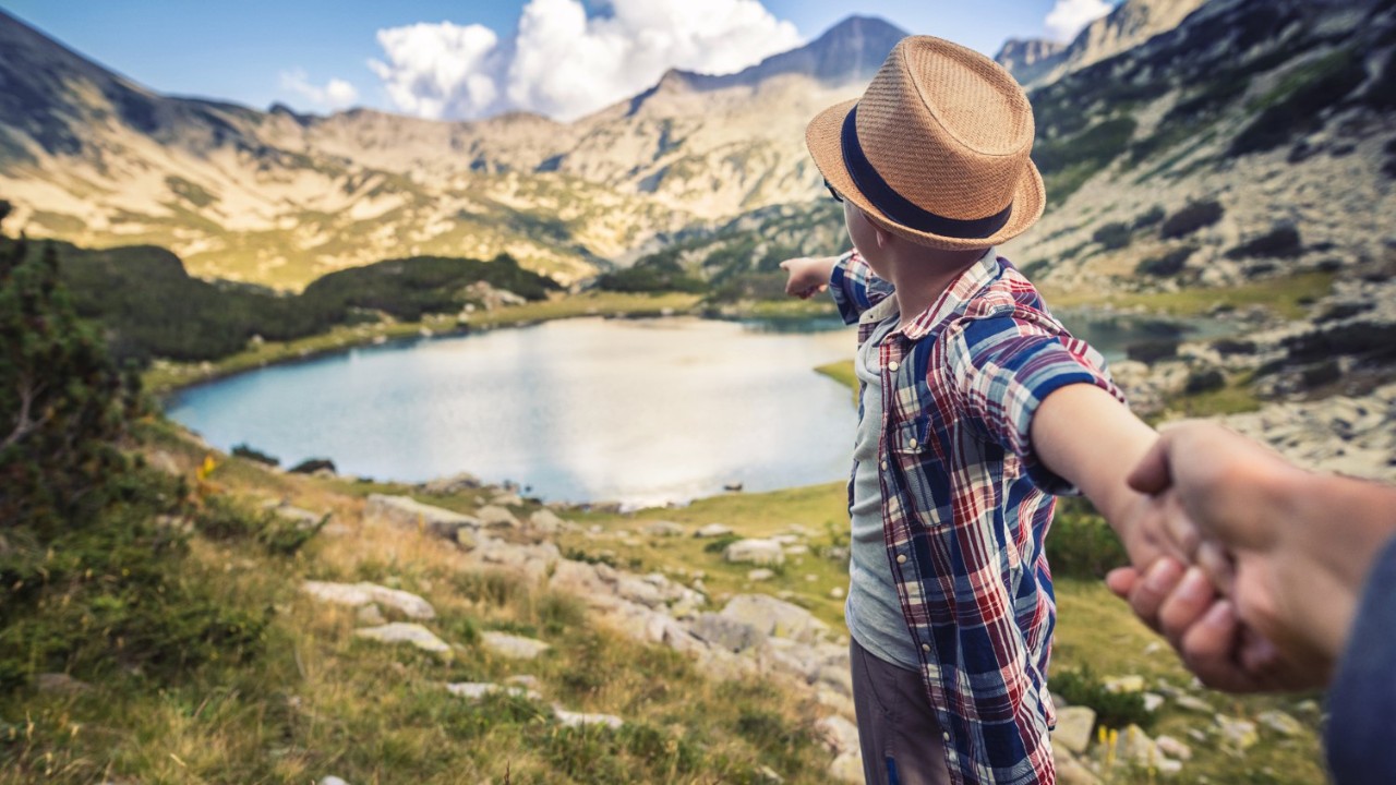 People holding hands in front of mountains.