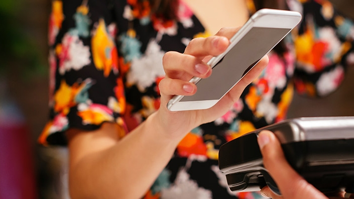 A woman paying with her mobile phone; image used for HSBC Singapore Debit Cards