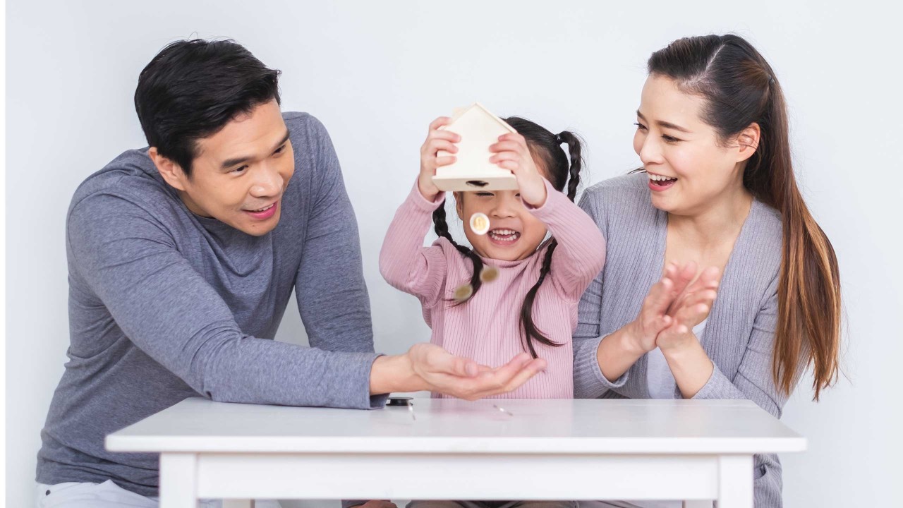 Parents and daughter holding piggy bank with coins falling.