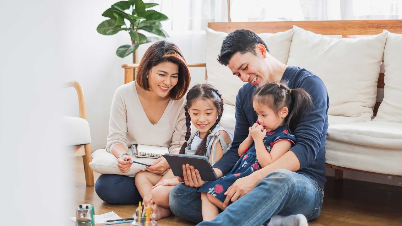 一个幸福的家庭正在一起使用平板电脑；图片使用于介绍“汇丰新加坡家庭财务保障”