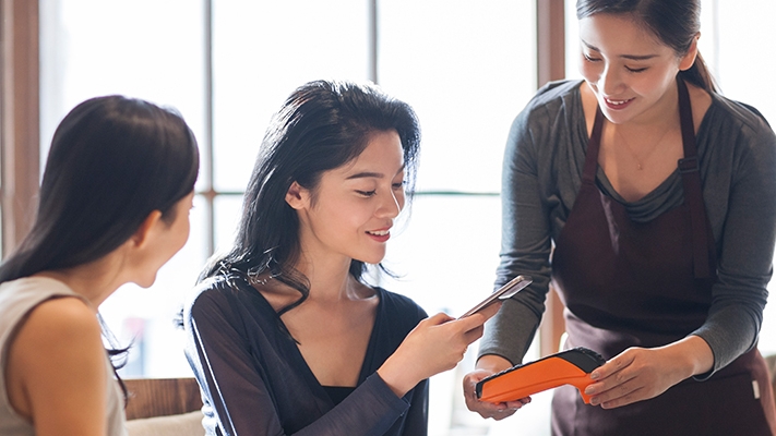 Two girls are using contactless payment.