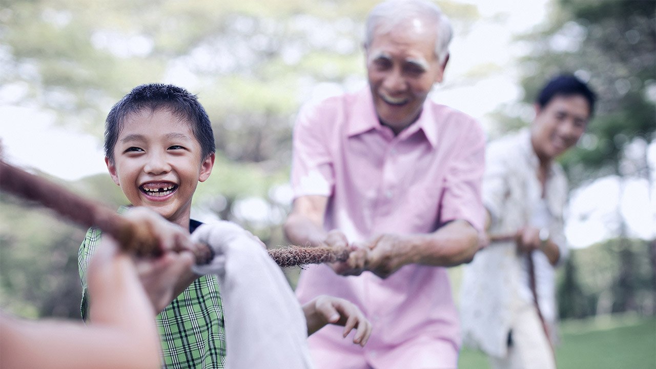 Grandfather is playing tug of war with grandson.