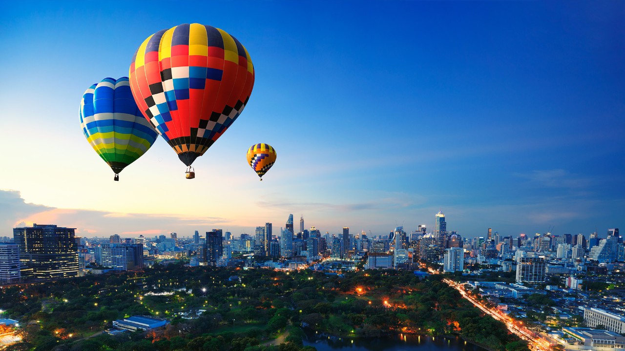 Three hot air balloons flying over a city; image used for HSBC Singapore Foreign Exchange Global View and Global Transactions