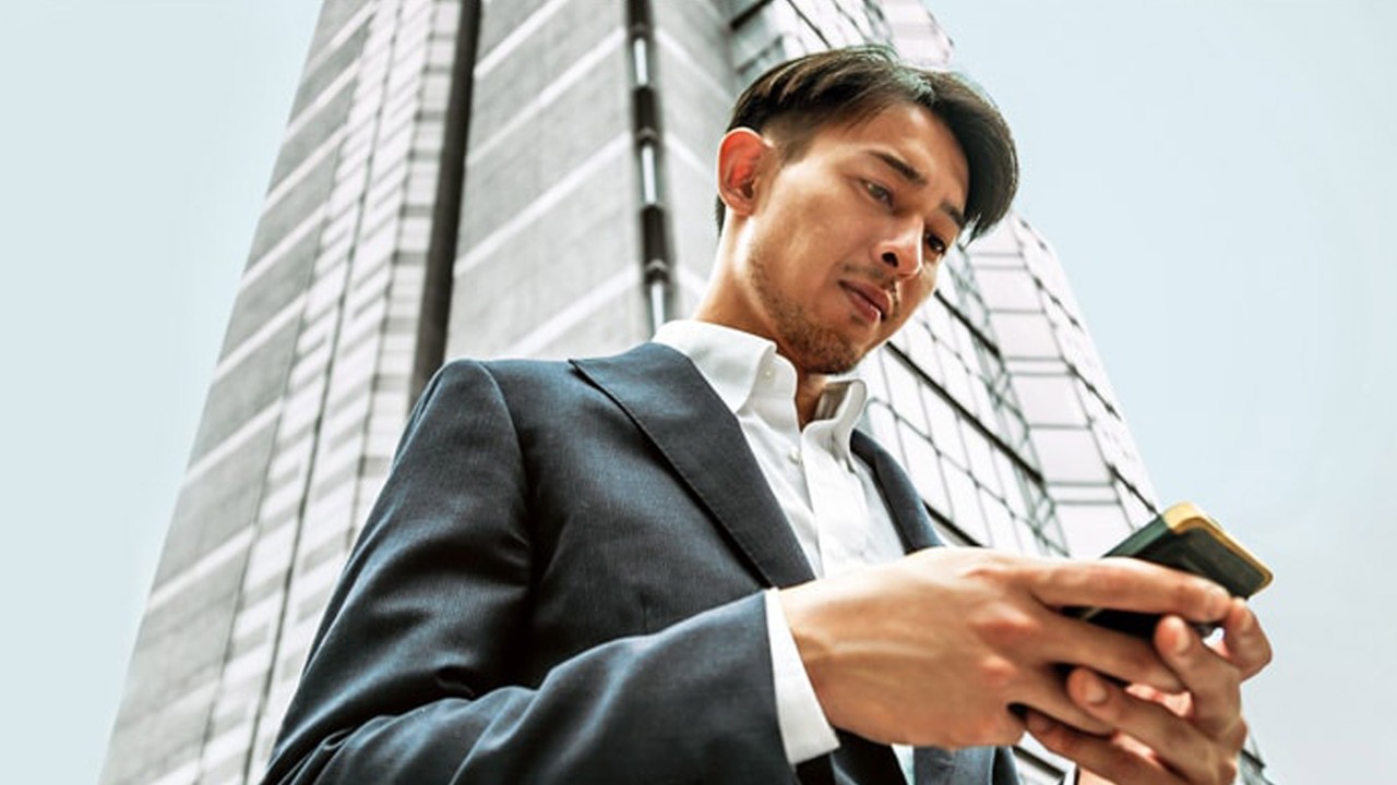 一位男士在使用手机；图片用于汇丰新加坡股票页面。