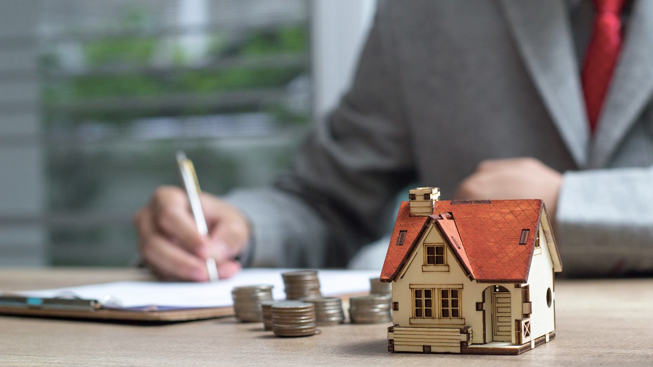 A man signing contract behind a house model; image used for HSBC Singapore Should you save or should you invest page.