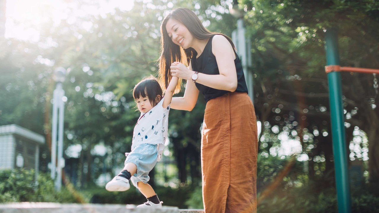 A joyful young mother holding hands of little daughter