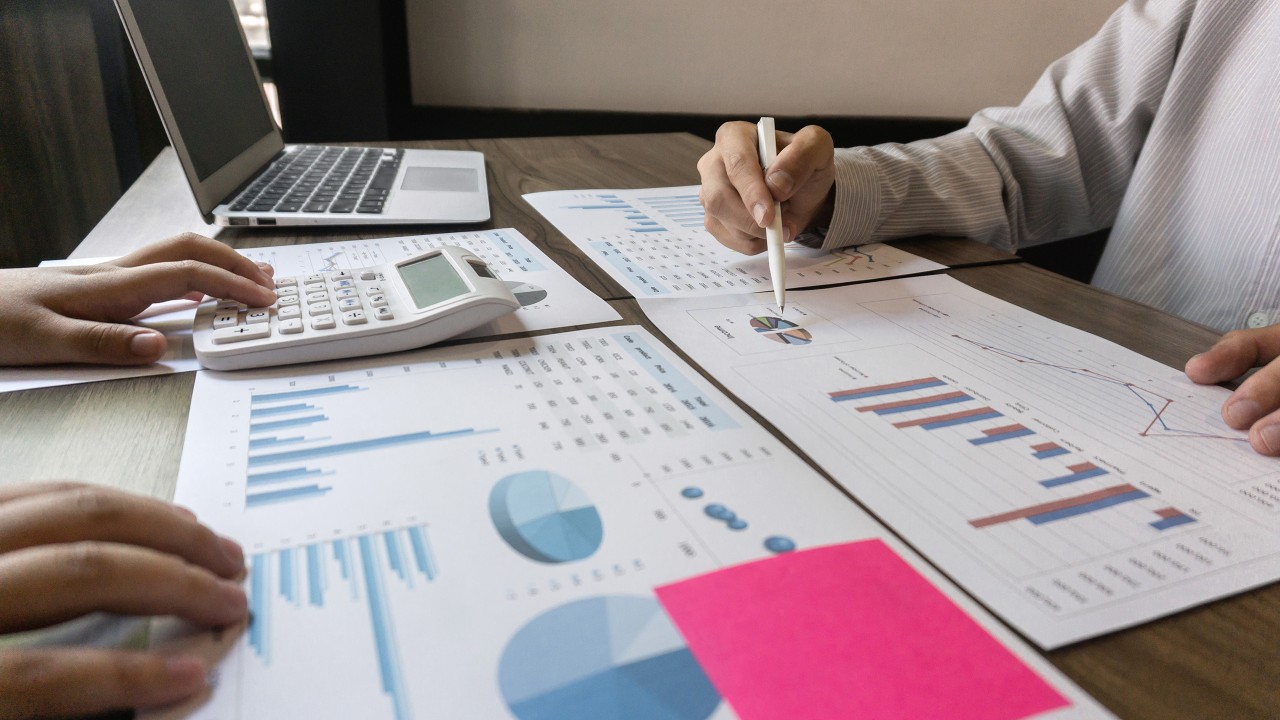 Two people with a calculator looking at portfolio charts