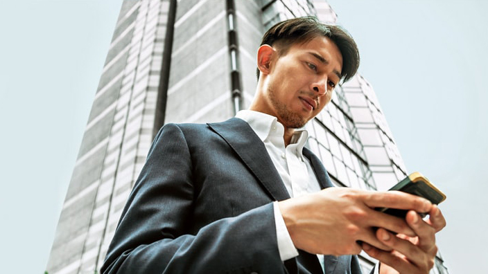 一位男士在使用手机；图片使用于汇丰新加坡证券交易页面。