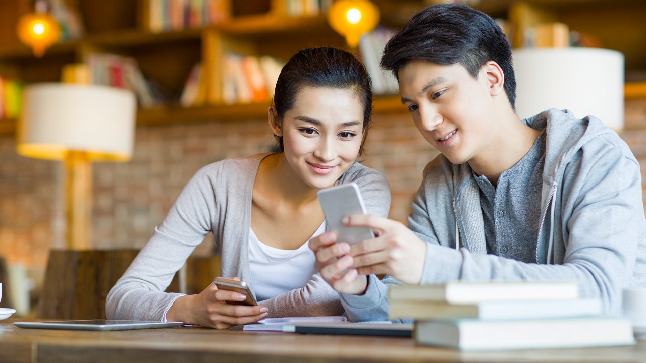 Two people are looking at a mobile phone; image used for HSBC Singapore Balance Transfer.