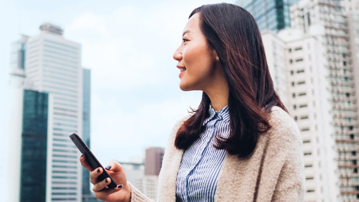 A women holding her smart phone in the city; image used for HSBC Singapore Unit trusts.
