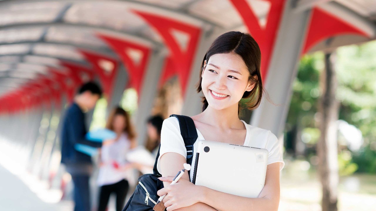 A university student holding latop; image used for HSBC Singapore Planning your child's education. 