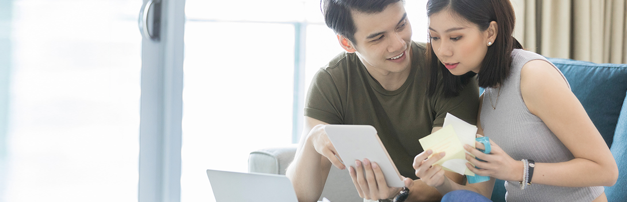 A couple looking at tablet with bills; image used for HSBC Singapore How to optimise your loan repayment strategy.