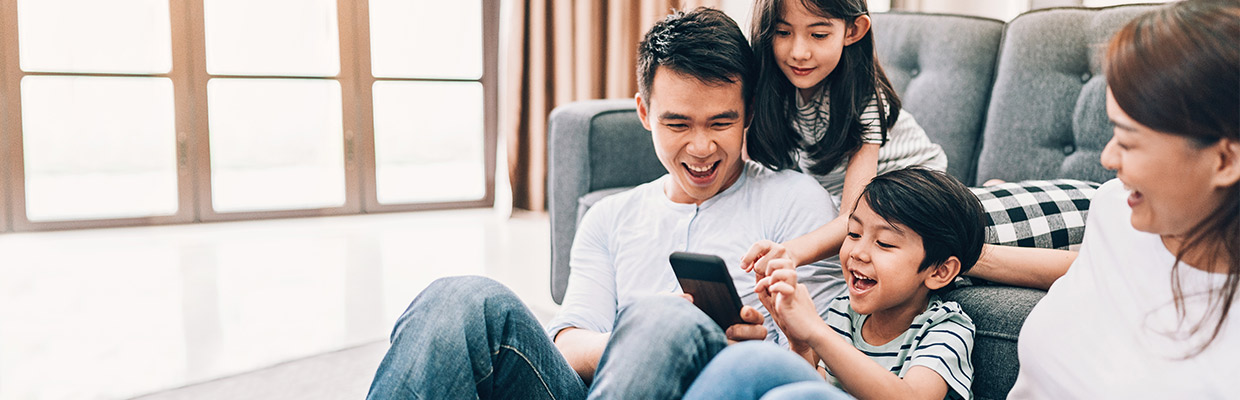 A family are playing on a mobile phone; image used for HSBC Wealth Dashboard