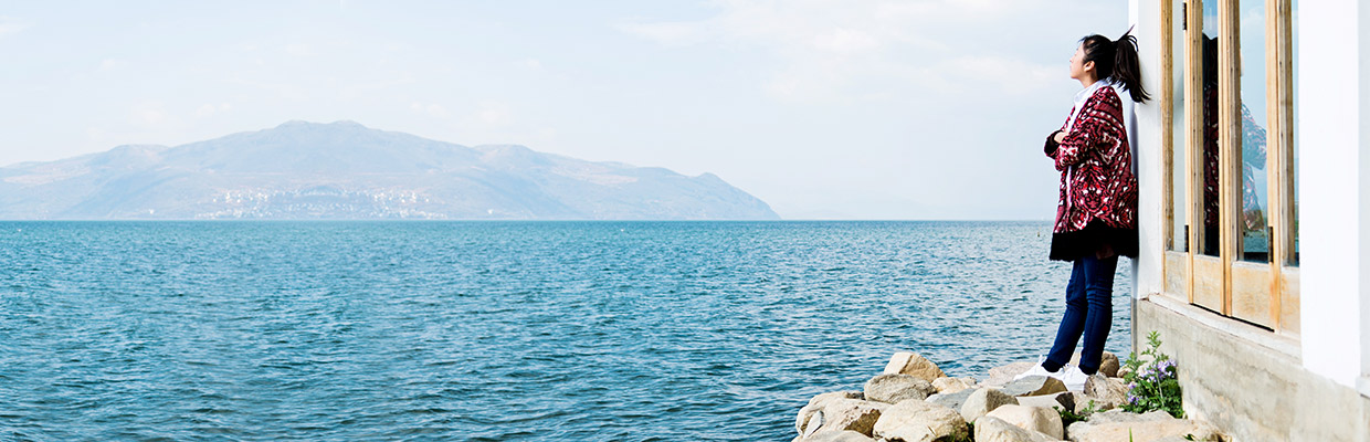 A girl is standing by the water; image used for HSBC Singapore Bonds