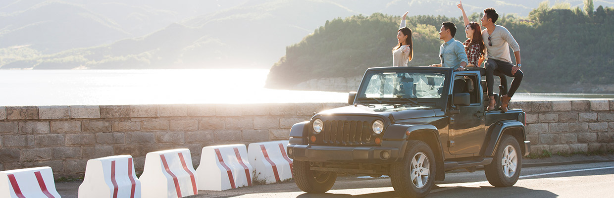 Men and women are standing on a car; image used for HSBC Car Insurance.