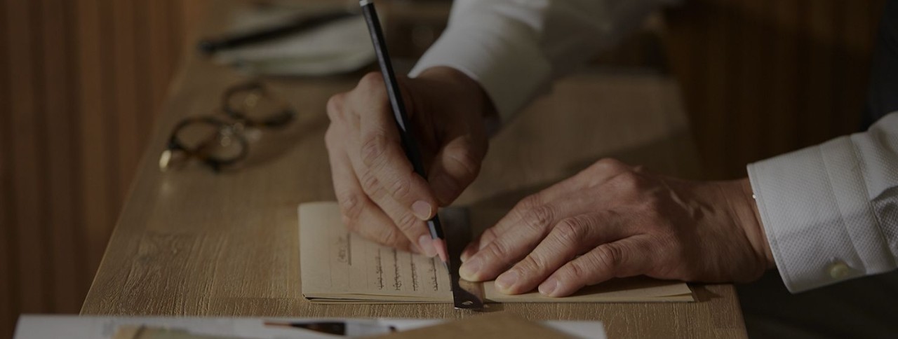 A man is writing on paper; image used for HSBC Singapore Visa Infinite credit card