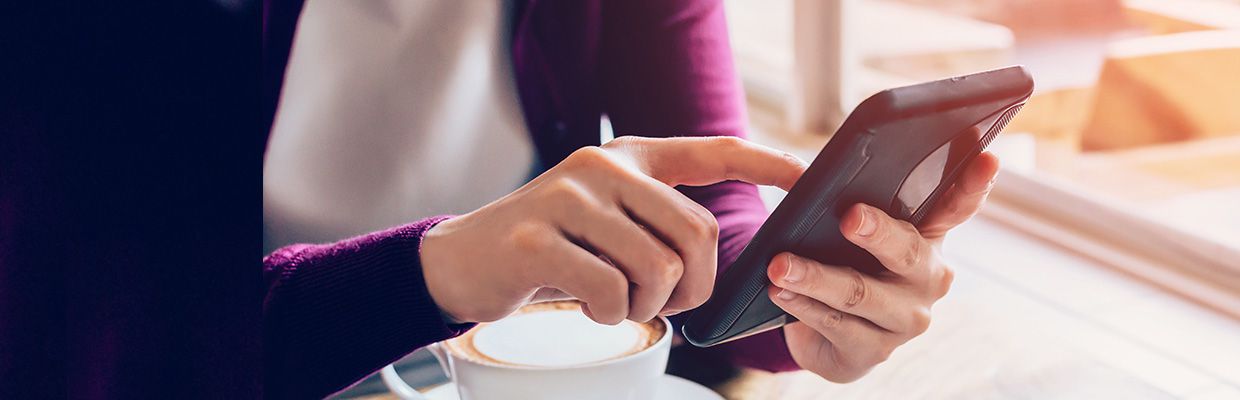 Using mobile phone in cafe; image used for HSBC Singapore PayNow page.