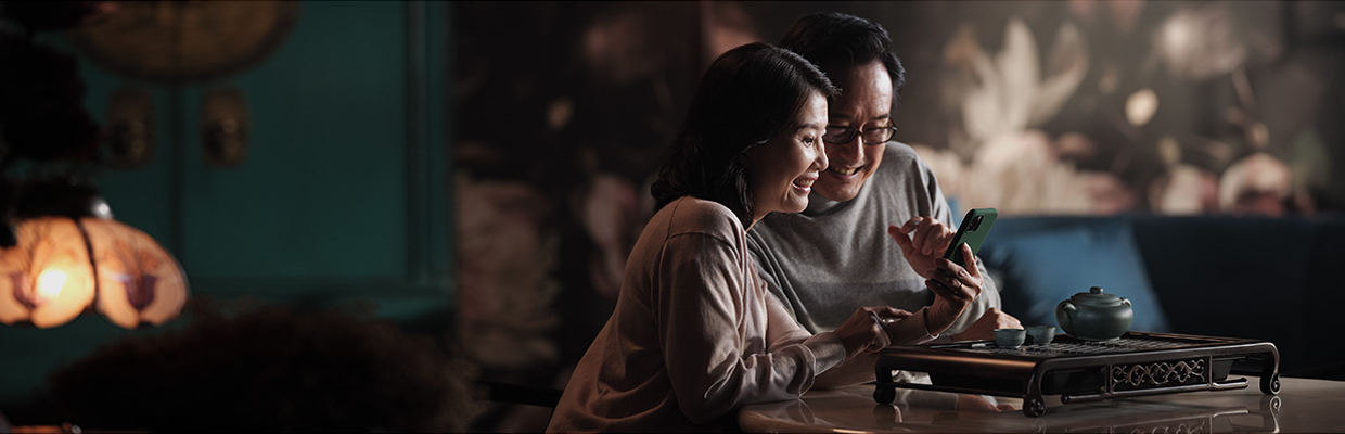 A couple looking at mobile phone; image used for HSBC Singapore Global Money Transfers. 