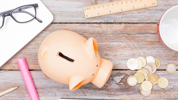 A piggy bank with coins, a passport, calculator and laptop; image used for HSBC Singapore Card Instalment Payment Plan