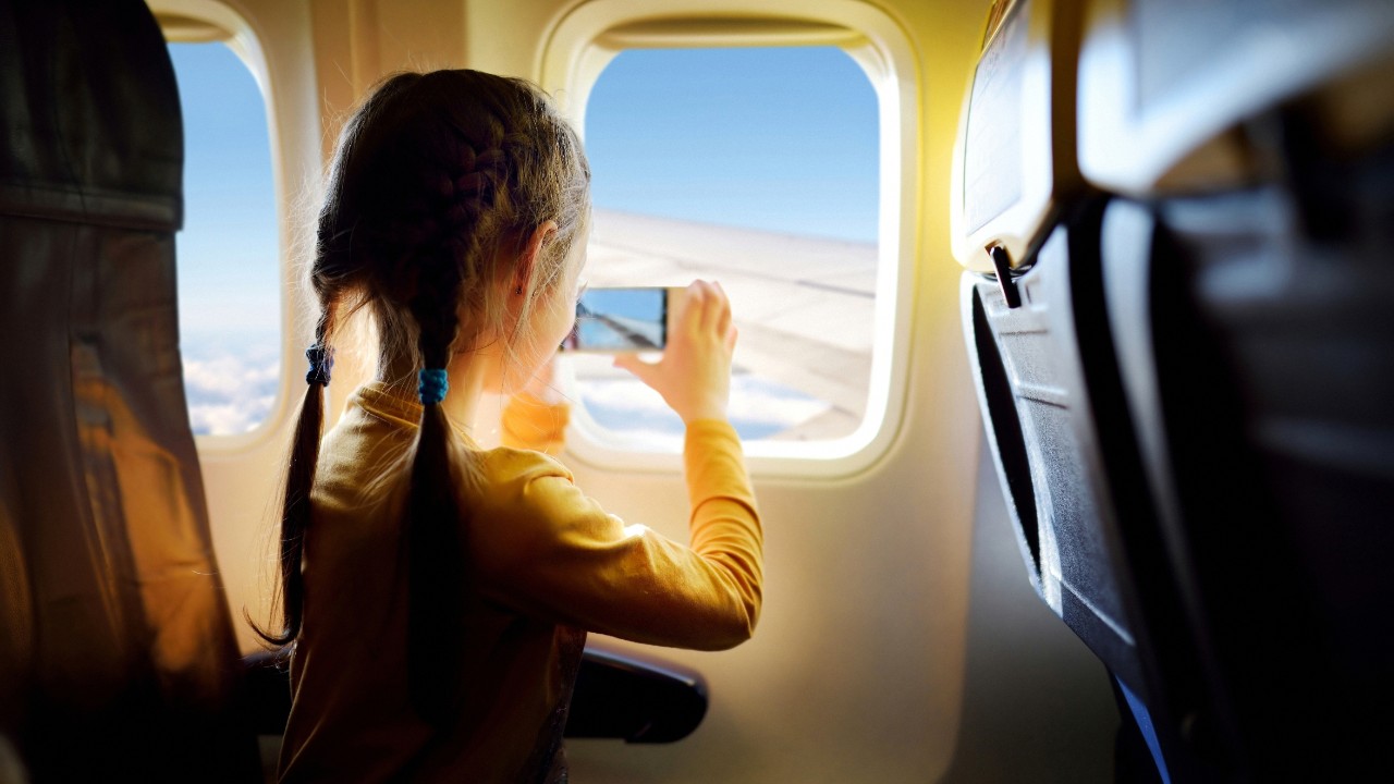 女孩向飞机窗外张望；图片使用于汇丰“移居之旅指南”指南文章页面