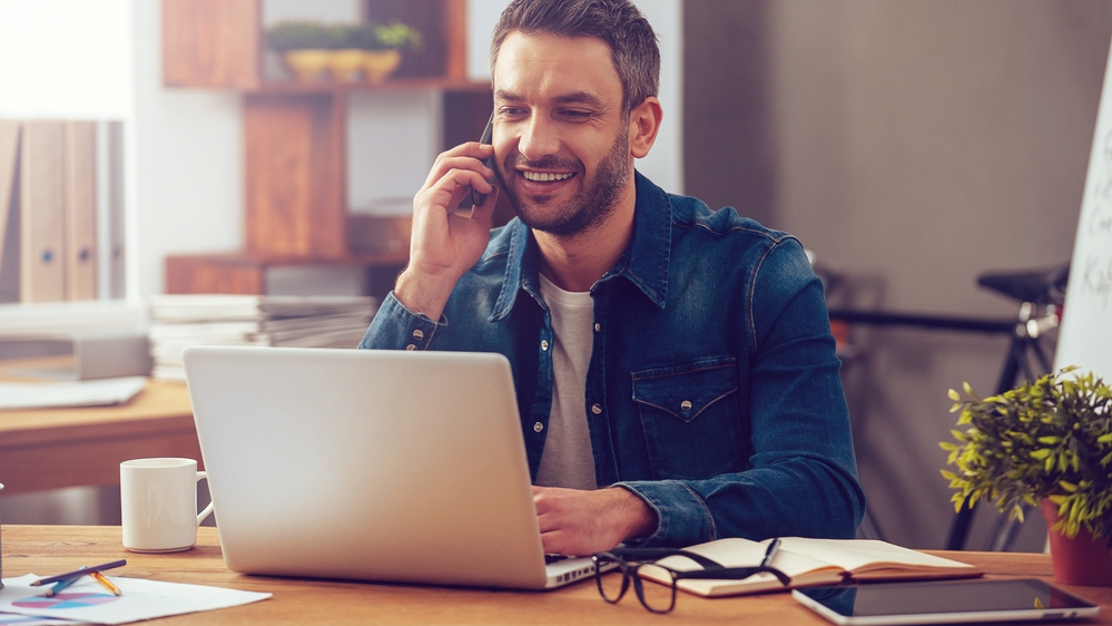 A man talks on phone while using a laptop; image used for HSBC Singapore International money transfers made easy article