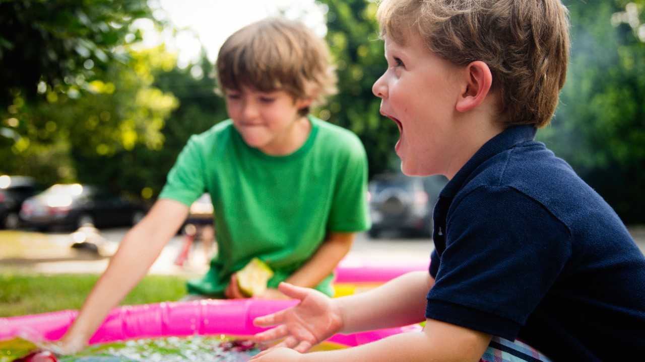 two young boys playing with inflatable pool in a park