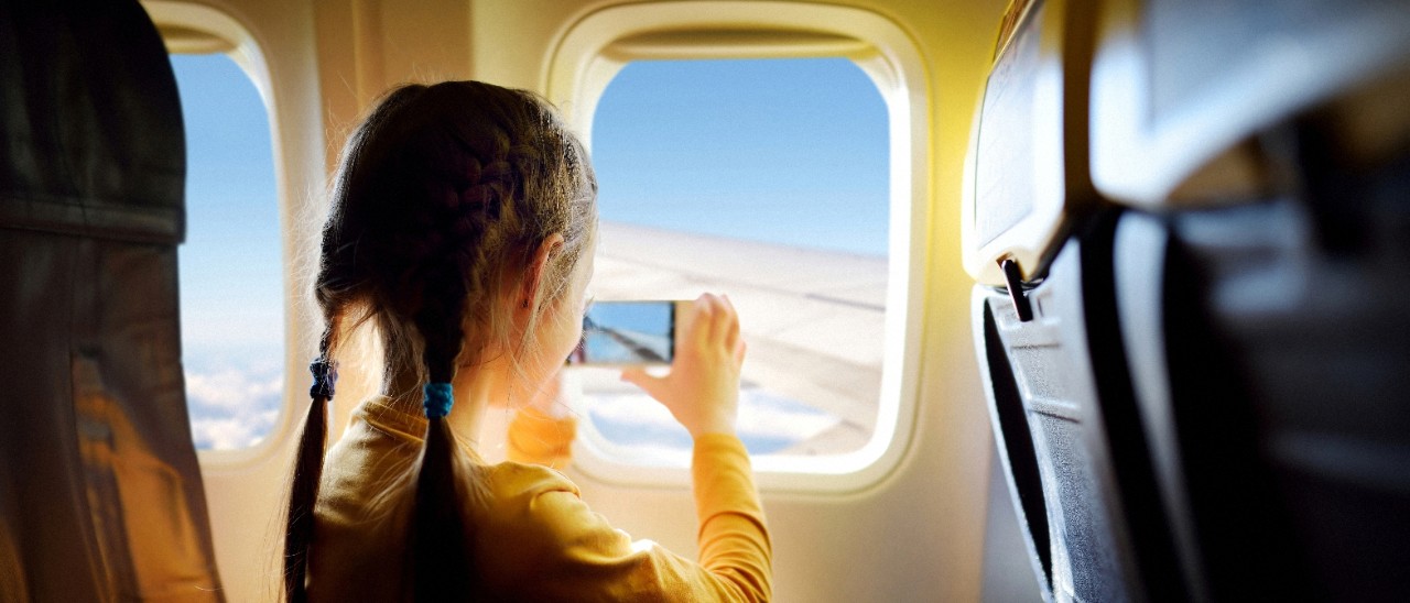 小女孩在拍摄飞机窗外的风景；图片使用于“汇丰移居之旅指南”文章页面