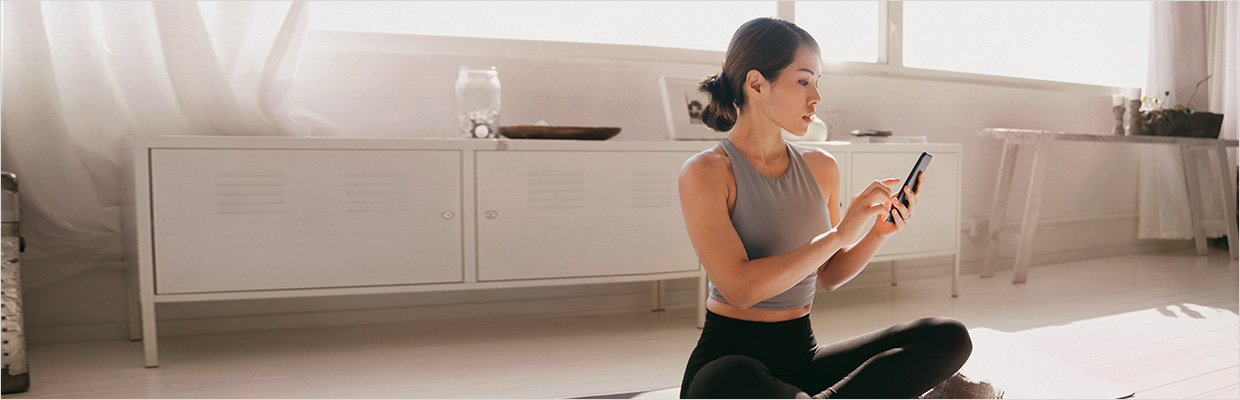 Woman using mobile phone in yoga mat; image used for HSBC Singapore Personal Loans.