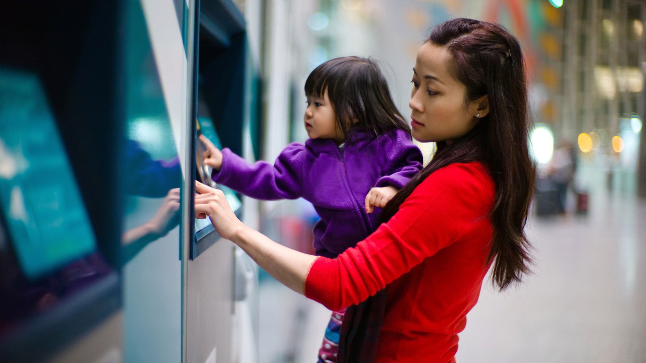 A mother is holding her daughter while using the atm; image used for HSBC Singapore Express Banking
