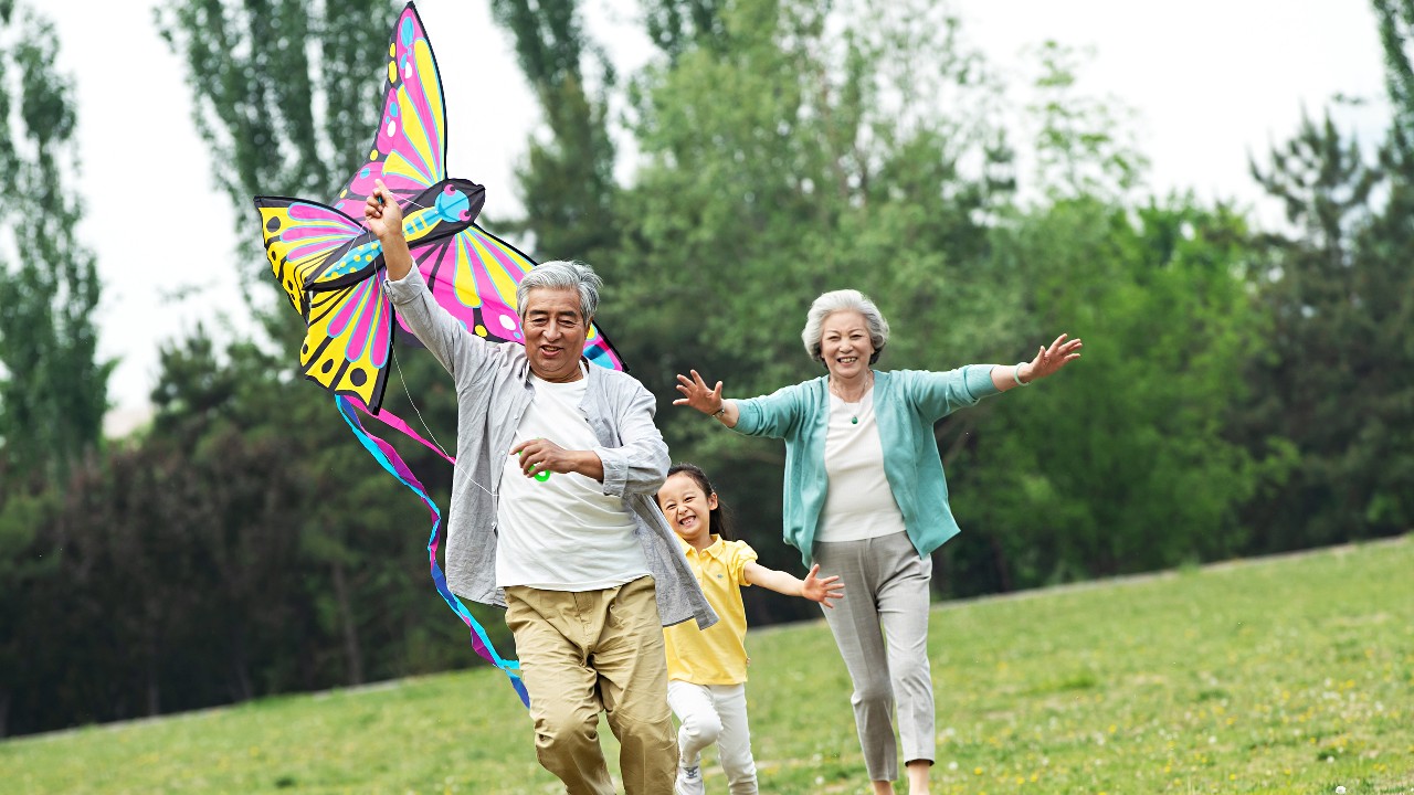 Couple and kid are flying a kite.