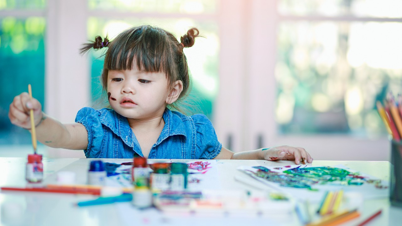 Girl painting with paintbrush.